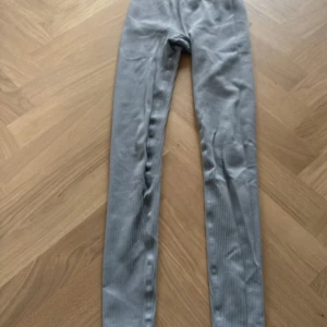 Grå ribbade leggings med hög midja - Snygga grå leggings med ribbad struktur och bred, hög midja som sitter skönt. Stretchigt material som formar sig efter kroppen och passar perfekt till chill eller träning. Enkel design utan synliga detaljer för en clean look.