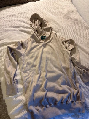 Beige hoodie från Alan Paine - Snygg beige hoodie från Alan Paine med mjukt stickat material och klassisk huva. Tröjan har långa ärmar och ribbade muddar vid ärmslut och nederkant. Perfekt för dig som gillar stilren och enkel design med en chill vibe.