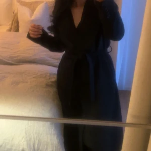 Svart kappa med bälte och bred krage - Säljer en svart kappa med bred krage och knytbälte i midjan. Jackan har en klassisk, lång siluett och är perfekt för dig som gillar stilrena och tidlösa plagg. Långärmad och med snygg omlott-look framtill. Den är perfekt just till vintern, samt för hösten. Den är köpt för ungefär 4500 :- säljer den för endast 1500:- 