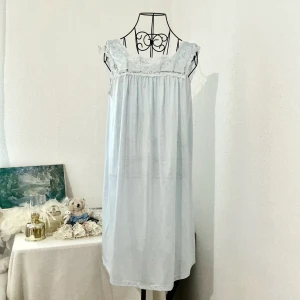 Ljusblå klänning med spets från Velrose - Söt ljusblå klänning från Velrose med broderade blommor och spetsdetaljer vid axlar och halsringning. Har lite fläckar på baksidan (se sista bild) men syns inte så jättetydlig. Materialet är tunt och något genomskinligt. Storlek S men passar S-M (34-38). Dockan är i storlek 34.