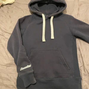 Svart hoodie från Russedress med huva - Svart hoodie från Russedress med stor huva och vita snören. Tröjan är i okej skick. Lite solblek på vissa ställen . Annars är tröjan i bra skick . Skön och varm.