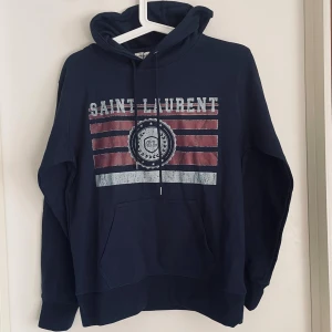 Saint Laurent Hoodie - Marinblå Saint Laurent Hoodie. Säljer då den inte passar mig. Helt sprillans ny. 