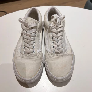 Vita Vans Old Skool sneakers (inte hel ny vita) - Säljer ett par klassiska Vans Old Skool sneakers i helvitt. Skorna har snörning, rund tå och platt sula. Ovandelen är i canvas med detaljer i vitt skinn längs sidan.  Användes kanske 2 gånger tvättade en gång och så kom denna färg