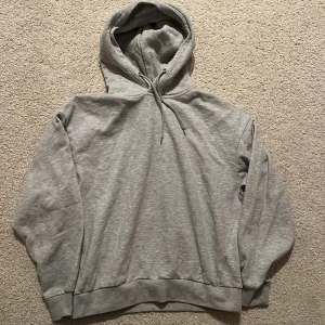 Grå hoodie från 157 med huva - Säljer en enkel och snygg grå hoodie från 157 i storlek S. Tröjan har huva med snörning, ribbade muddar och en loose passform. Perfekt för chill dagar och när du vill vara bekväm. Materialet är mjuk bomull och polyester.