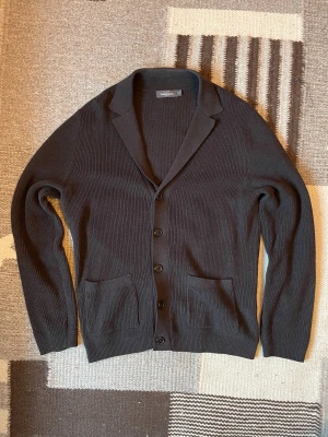 Dressmann Cardigan - Brun cardigan från Dressmann i storlek M. Två praktiska fickor framtill och långärmad modell. Perfekt för dig som gillar stilrena och enkla plagg. Hör av dig vid minsta fundering:)