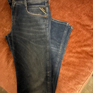 Replay Hyperflex jeans blå 30/34 - Snygga blå Replay Hyperflex jeans med klassisk femficksdesign och coola detaljer på bakfickorna. Stretchigt material för extra komfort och passform. Midja med knapp och dragkedja, samt Replay-logga på fickan. Perfekt för dig som gillar stilrena jeans.  