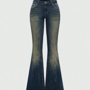 Broderade bootcut jeans med kors - Snygga mörkblå bootcut jeans med hög midja och broderade detaljer i vitt och silver på bakfickorna och linningen. Jeansen har en klassisk femficksdesign och är tillverkade i jeansmaterial med cool faded effekt. Perfekt för dig som vill sticka ut med unika detaljer.