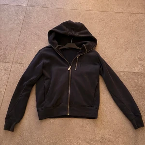 Mörkblå Sail Racing zip - Mörk blå hoodiejacka från Sail Racing med hel dragkedja och en extra zipficka på bröstet. Jackan har en stor huva, ribbade muddar och är tillverkad i mjuk bomull. Skick 8,5/10