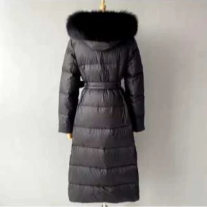 Svart lång dunjacka med päls från Vivanilla  - Snygg svart lång dunjacka med fluffig päls runt huvan och bälte i midjan. Jackan är quiltad och har långa ärmar, perfekt för kalla dagar. Stilsäker look med markerad midja och extra värme tack vare dunfyllningen och pälsdetaljen.