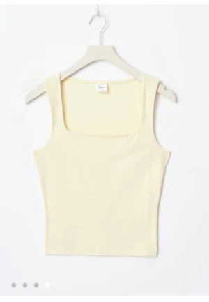 Ljusgult linnetopp med fyrkantig hals - Säljer en stilren ljusgult linnetopp från Monki med fyrkantig halsringning och breda axelband. Toppen är ärmlös och har en slim passform som sitter snyggt mot kroppen. Perfekt att matcha med jeans eller kjol för en clean look. Slutsålt!!!