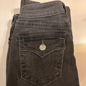 True Religion Becca Bootcut Jeans  - Hejj säljer mina mörkgråa jeans från True Religion, modell Becca med bootcut och midwaist. Snygga kontrastsömmar och ikonisk fickdesign med silverfärgad knapp💘