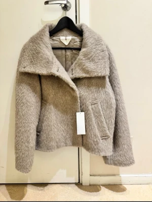 Jacka från Arket  - Jacka i ull och alpacka blandning med ståkrage från Arket ! Den är enkelknäppt och helfodrad. Helt ny med prislappen på . Färgen är mer beige i verkligheten. Storlek 34. Slutsåld på hemsidan.