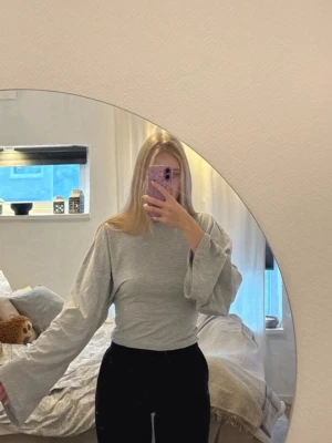 Wide sleeve LS top  - Grå croppad topp från Nelly med vida långa ärmar och rund halsringning.  Säljer en grå topp från Nelly men vida ärmar och tight vid midjan. Jättefin utan skavanker, använd 1 gång. Wide sleeve LS top  Storlek S