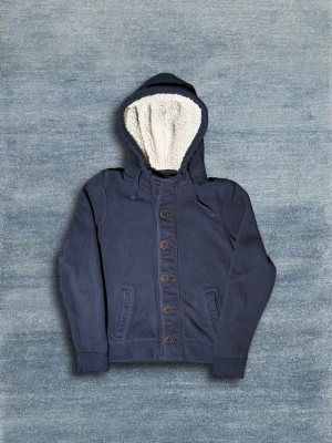 Hollister Cardigan - Snygg blå cardigan från Hollister med skön fodring. Tröjan är i bra skick. Hör av dig om du har några frågor eller vill ha fler bilder!🙌