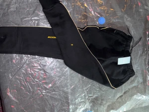 NOCTA x Nike mjukisbyxor - Svarta mjukisbyxor från Nike NOCTA med gul logga och text på benet. Byxorna har vita kontrastlinjer längs sidorna, resår och snörning i midjan samt muddar vid bensluten.