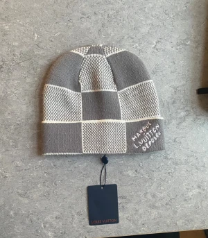 Grå rutig mössa  - En grå stillren mössa passande för de kalla vintertiderna och perfekt för dig som söker något snyggt och varmt. Helt oanvänd med lapp, pris kan diskuteras.