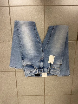 Ljusblå tiger of Sweden  jeans herr W29 L32 - Säljer ett par ljusblå tiger of Sweden  jeans med klassisk femficksdesign och snygga slitningar. Jeansen har smal passform med tighta ben och smal fot, samt bruna detaljer vid linningen. Perfekta för dig som gillar en modern och clean look.