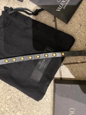  Valentino armband - Svart valentino armband, låda, dustbag, kuvert från valentino samt extra nitar medföljer. Skicket visas i bilderna. Ställ gärna frågor om du funderar över något!