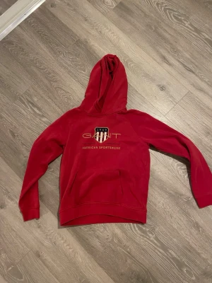 Gant hoodie  - Röd gant hoodie men den klassiska gant logan i mitten av tröjan. Tröjan är i storlek S och är i ett bra skick. 