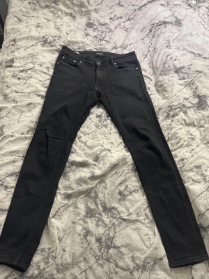 Svarta skinny jeans Jack & Jones - Svarta skinny jeans från Jack & Jones, modell Liam. Klassisk femficksdesign med smal passform och låg midja. Jeansen är tillverkade i stretchig bomullsblandning för extra komfort och har diskreta svarta sömmar och detaljer.