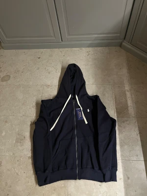 Marinblå polo Ralph lauren zip hoodie  - Säljer en marinblå polo Ralph lauren zip hoodie. Den är i helt ny skick och säljes för ett riktigt bra pris. Storlek S men passar även M😊.                                                 Kom privat vid frågor å funderingar💸