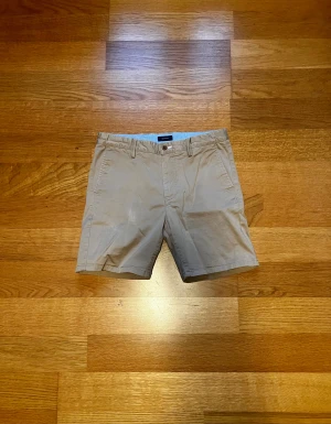 GANT Shorts, Beige, 158-164, Bra Skick - Tja! Säljer ett par snygga och klassiska shorts från Gant, då de har blivit för små. Shortsen är gjorda av bomull, använda flera gånger och i bra skick. Perfekt stilplagg för sommaren. Vid frågor eller för fler bilder - skicka gärna ett meddelande. Mvh William