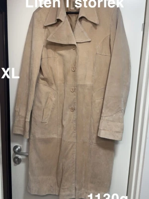 Beige mocka kappa med knappar XL - Snygg beige kappa i mjuk mocka med klassisk krage och knäppning med fyra knappar framtill. Jackan har två fickor och är helfodrad i matchande beige ton. Perfekt för dig som gillar stilrena och tidlösa plagg med lite extra edge.🌸Rejäl och tung kappa från veromoda. Står att det är soft pig split. Tyvärr missfärgad, vet inte om det går att fixa. Saknar skärp. Storlek XL.