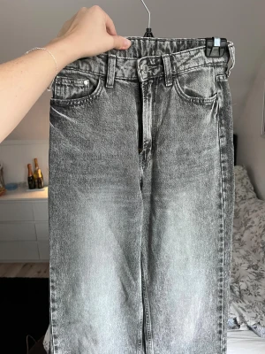Grå jeans från H&M, storlek 34 - Snygga grå jeans med en klassisk femficksdesign och raka ben. De har en knapp och dragkedja framtill samt hällor för bälte. Perfekta för en avslappnad stil. Använda max 5 gånger. Önskar du veta exakta mått? Tveka inte att höra av dig!