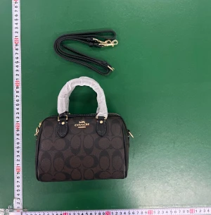 Brun handväska  - Snygg brun handväska från Coach med klassiskt logomönster och guldfärgade detaljer. Väskan har två handtag och en avtagbar axelrem, perfekt för att bära både i handen och över axeln. Tillverkad i skinn med dragkedja upptill och stilren form.