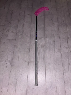 Innebandyklubba Unihoc Unislim pro  - Bilderna visar en Unihoc innebandyklubba med rosa evolite blad och grått grepp från oxdog. Left vinkel 95% carbon fiber och 5% glasfiber, kan gå ner i pris vid snabb affär 