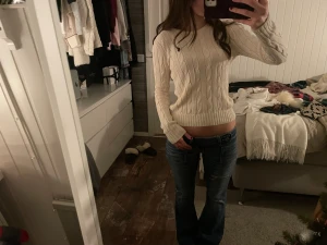 Vit kabelstickad tröja från Ralph Lauren - Säljer en snygg vit kabelstickad tröja från Ralph Lauren med klassisk rund hals och långärmad passform. Tröjan har det ikoniska Polo-logot på bröstet och är gjord i mjuk bomull. Perfekt till jeans och har en slim, figurnära siluett.