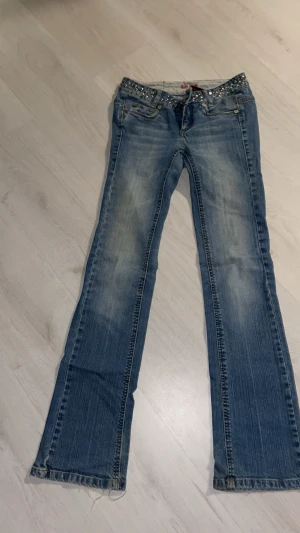 Blå jeans med nitar och bootcut - Snygga blå jeans från bikbok med coola nitar på linningen och bakfickorna. Bootcut-modell med slitningar. Klassisk femficksdesign och dragkedja fram. Perfekt för dig som gillar att sticka ut med detaljer. Kom gärna med bud😊