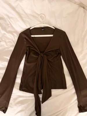 Brun långärmad topp med knyt - Säljer en brun långärmad topp från Gina Tricot med snygg knytning framtill och v-ringad hals. Knappt använd 