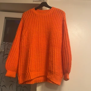 Oversized orange stickad tröja Divided från H&M - Säljer en chunky stickad tröja från Divided i en riktigt poppig orange färg. Tröjan har oversized passform, grovstickat mönster och långa ärmar med breda muddar. Perfekt för att liva upp höst- och vinterlooken! Observera tröjan har en liten smutsfläck på vänster arm som går att tvätta!