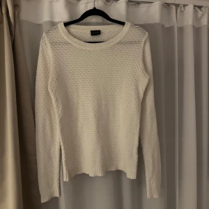 Vit stickad tröja från Vila XS - Säljer en vit stickad tröja från Vila i storlek XS. Tröjan har ett diskret mönster, rund halsringning och långa ärmar. Perfekt för lager-på-lager och passar till allt. Ribbstickade muddar vid ärmslut och nederkant ger en snygg finish.
