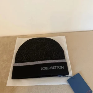 Mössa - Snygg svart mössa från  med grå kant Mössan har diskret mönster med klassiska -symboler och är tillverkad i mjukt stickat material som håller dig varm