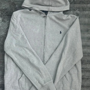 Ralph lauren zip hoodie  -  Grå Ralph Lauren zip hoodie – storlek XL (barn, passar ca 170 cm) 🩶  Superfin hoodie i klassisk grå färg med ikoniska 🐎 Polo-loggan broderad på bröstet. Mjuk, skön och sitter riktigt snyggt på! 🔥 Kvalitén är top notch – nästan som ny 💫 Perfekt för både chill och stiliga outfits 👌  💨 Bra passform, lyxig känsla och tidlös look!  📏 Storlek: XL (barn) – motsvarar ungefär 170 cm 💎 Skick: Jättebra skick, knappt använd