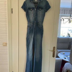 Jeans jumpsuit bootcut bershka  - Snygg jeans jumpsuit i klassisk blå denim med korta ärmar, krage och dragkedja framtill. Fickor på bröstet och bak, samt markerad midja och långa ben med lätt utsvängda ben. Perfekt för dig som gillar en cool och avslappnad stil
