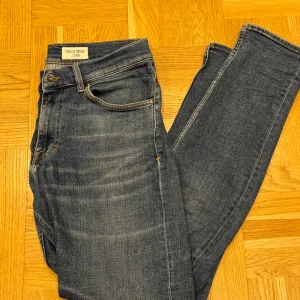 Blå jeans Tiger of Sweden Evolve 31/32 - Blå jeans från Tiger of Sweden i modellen Evolve. Rätt bra skick förutom en slitage i grenen. Hör av er vid frågor eller funderingar.