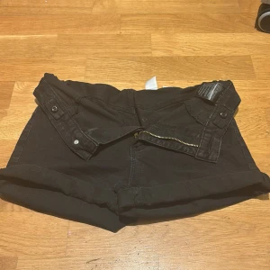 Svarta denimshorts från &Denim - Svarta shorts i denim från &Denim med klassisk femficksdesign, uppvikta benslut och dragkedja framtill. Snygga detaljer med knappar i midjan och en liten Peanuts/Snoopy-etikett på insidan. Perfekta för en chill sommarlook.