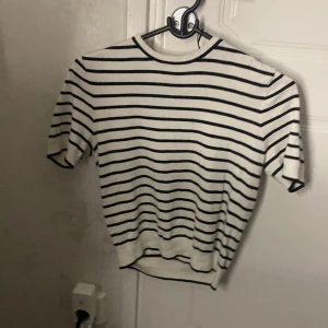 Randig vit och svart tröja S - Vit tröja med svarta horisontella ränder och rund hals. Tröjan har korta ärmar och ribbad nederkant. Perfekt för dig som gillar en klassisk och stilren look med lite fransk känsla.