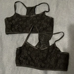 Svarta spetslinnetoppar från beTEEN - Två svarta linnetoppar från beTEEN i storlek 170. Topparna har ett blommigt spetsmönster och tunna axelband. Utsidan är i spets med 90% polyamid och 10% elastan, fodret är i mjuk bomullsmix. Perfekta för en snygg lager-på-lager-look.