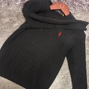 Svart stickad tröja Polo Ralph Lauren - Svart stickad tröja från Polo Ralph Lauren med klassisk röd logobroderi på bröstet.