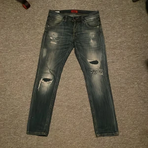 Slim fit blå slitna jeans 29/30 jack n Jones - Snygga blå jeans från Slim/Glenn i storlek 29/30 med slim fit. Feta slitningar och fet tvätt. Inga defekter, bara slitningar från affären. Pm vid frågor eller funderingar!