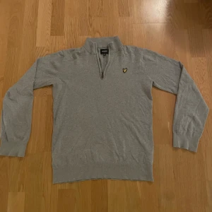 Grå half zip tröja Lyle & Scott - Snygg grå långärmad tröja från Lyle & Scott med half zip och klassisk gul logga på bröstet. Tröjan är i mjuk bomull och har ribbade muddar vid ärmslut och nederkant. Perfekt för dig som gillar stilren och enkel design. Hör gärna av er vid frågor! Användt fåtal gånger.