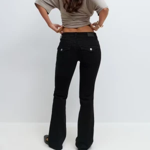 Svarta bootcut jeans från Gina Tricot - Ett par svarta jeans från Gina Tricot med bootcut och låg midja. Dem är uppsprättade vid slutet av jeansen som ger några extra centimeter i längden. 