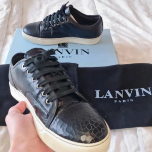 Lanvin Captoe - Svarta melerade Lanvins. Skick ny skick endast använda fåtal gånger. Pris 1899 inte huggit i sten. Hör av er vid frågor box ingår inte.