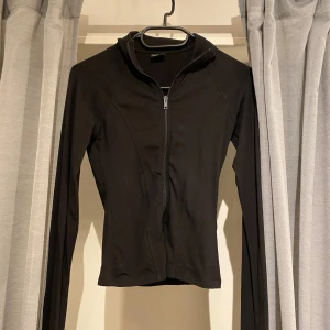 Svart ziptröja från Gina Tricot XS - Svart långärmad ziptröja från Gina Tricot i storlek XS. Tröjan har dragkedja framtill, hög krage och tumhål i ärmsluten för extra chill vibe. Materialet är mjukt och stretchigt, perfekt för lager-på-lager. Snygg och enkel att matcha med allt. Den är i deras soft touch kollektion