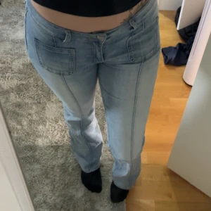 Ljusblå madlady jeans  - Ljusblå jeans med utsvängda ben och stora fickor fram samt bakfickor med lock och knapp. Jeansen har låg midja och är tillverkade i klassiskt denimtyg. Perfekta för en avslappnad och trendig look.