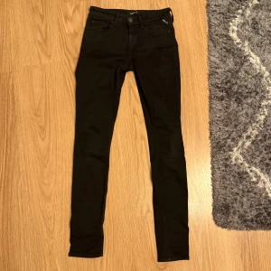 Svarta Replay Hyperflex skinny jeans - Svarta Replay Hyperflex jeans med skinny passform och klassisk femficksdesign. Stretchigt jeanstyg som sitter tajt och följer kroppen. Diskret Replay-logga på fickan och bakre läderpatch. Perfekt för dig som gillar stilrena och slimmade jeans.
